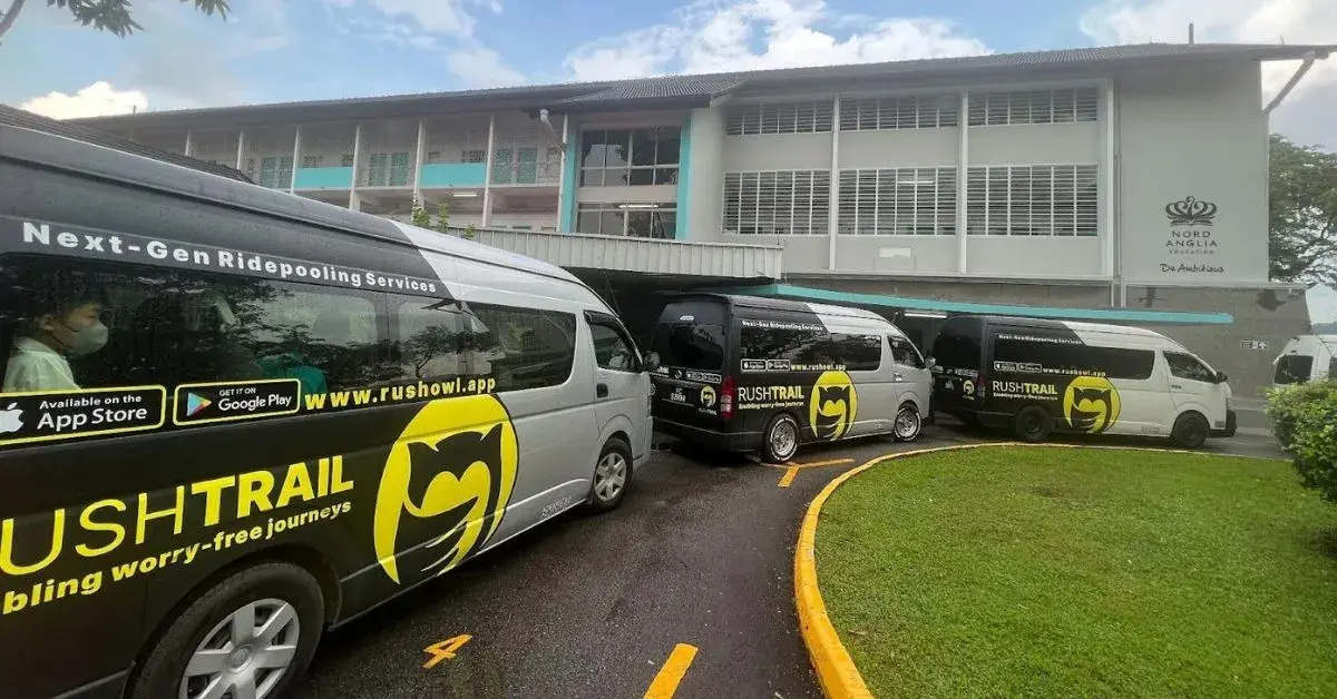 A fleet of RushTrail vans parked in front of a school